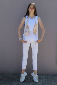 Full length portrait of a smiling girl standing against wall