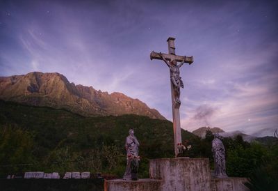 Cross and statues against sky