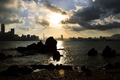 Silhouette rocks by sea against sky during sunset