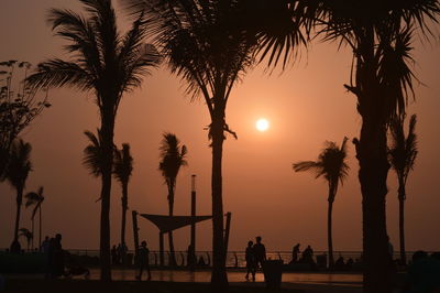 Silhouette people on promenade against sky during sunset