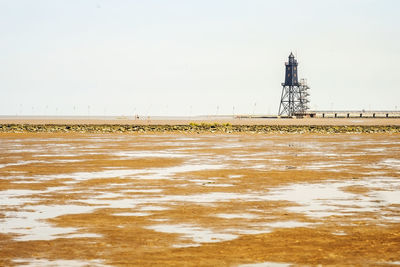 Lighthouse on beach against sky