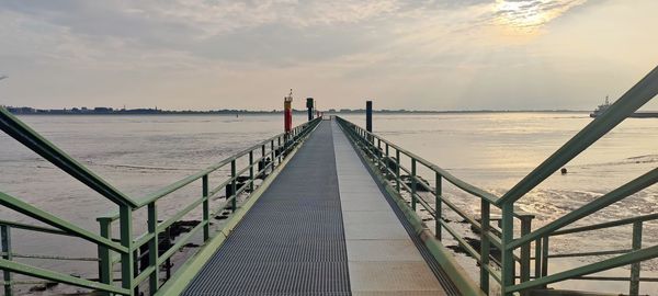 Pier over sea against sky during sunset