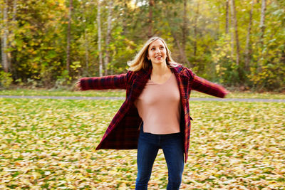 Young woman with umbrella walking on autumn leaves