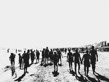 Group of people on beach against clear sky