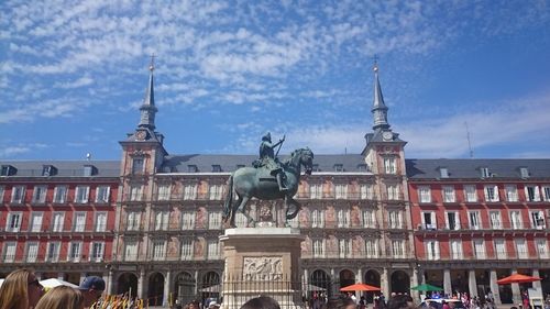 Statue in city against cloudy sky