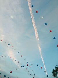 Low angle view of balloons flying against cloudy sky