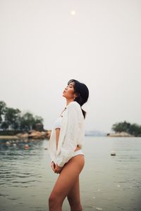 Woman wearing bikini standing in sea against clear sky