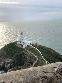 Lighthouse by sea against sky