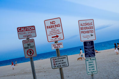 Signs at beach against sky
