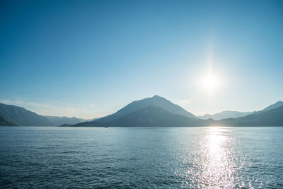 Scenic view of sea and mountains against blue sky