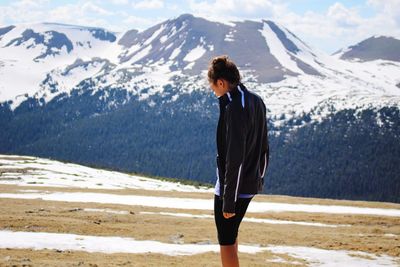 Side view of woman standing against snowcapped mountain