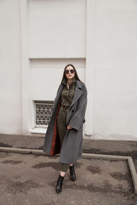 Female fashion model, posing for a full length photo, wearing green suit, urban fashion photography