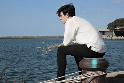 Side view of man looking at sea against sky