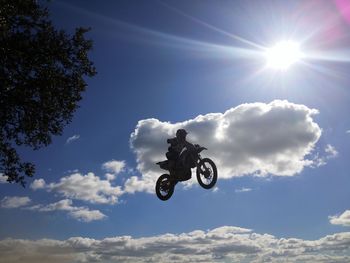 Low angle view of motocross racer performing mid-air stunt against sky