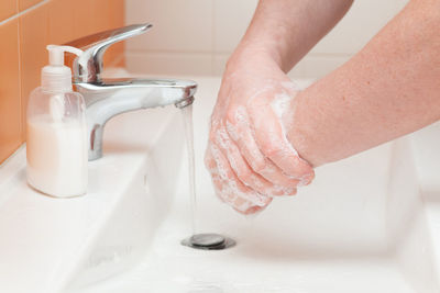 Close-up of person washing hands in sink