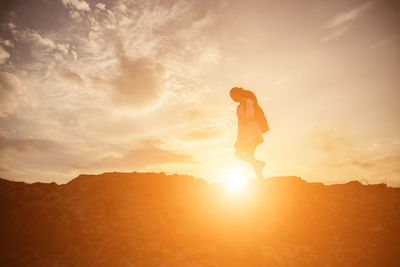 Man standing on mountain against sky during sunset