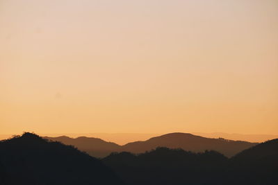 Scenic view of silhouette mountains against orange sky