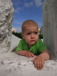 Cute boy looking away while lying on rock