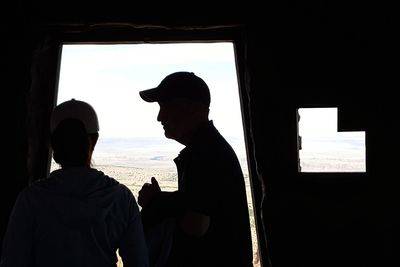 Rear view of silhouette man looking through window