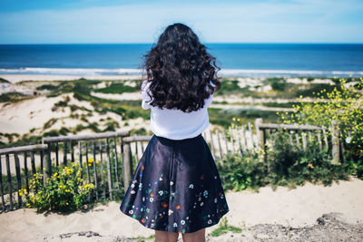 Rear view of woman standing at beach