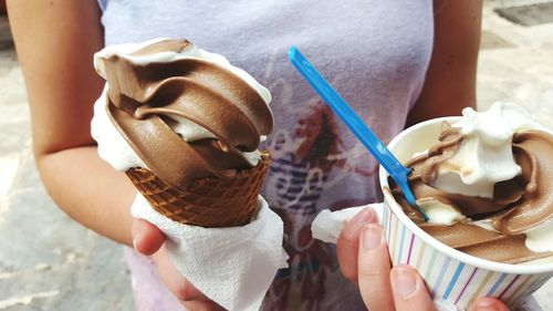 Midsection of woman holding ice-cream in hand