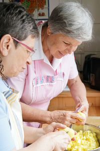 Senior women cutting potatoes in kitchen home