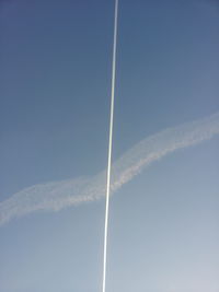 Low angle view of vapor trail against clear blue sky