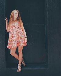 Young woman standing against wall