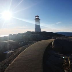 Lighthouse by sea against sky during sunset