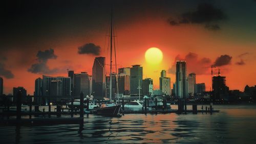 Scenic view of river by buildings against sky during sunset