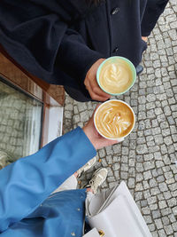 Low section of people holding coffee cup latte art