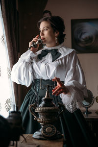 Beautiful woman in vintage blouse costume with retro phone. historical dresses, vintage outfits