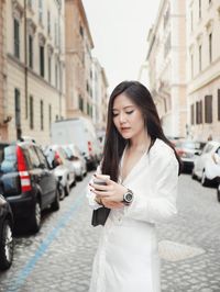 Young woman using phone while standing on street