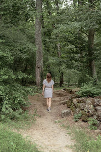 Back view of a woman walk along the forest in the early misty morning