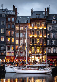 Boats moored in canal by buildings against sky