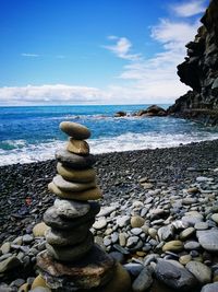 Stack of stones on beach against sky