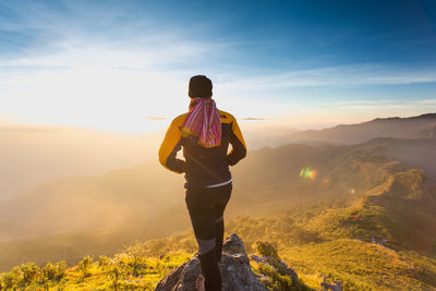 Rear view of man looking at mountains against sky