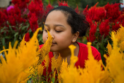Close-up of girl smelling flowers on plants