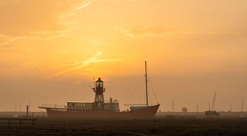 Silhouette ship moored on sea against sky during sunset