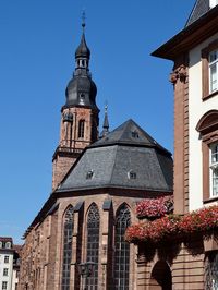 Low angle view of clock tower amidst buildings in germany against blue sky