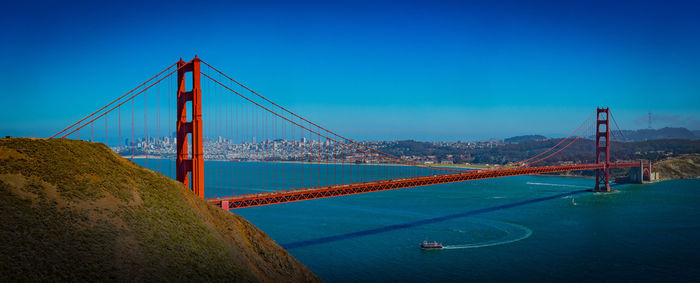 Suspension bridge over sea against blue sky