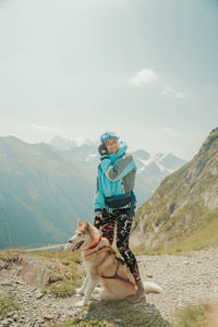 Man with dog on mountain against sky