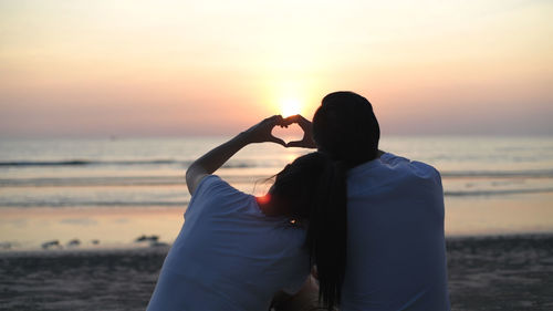 Rear view of couple on beach during sunset