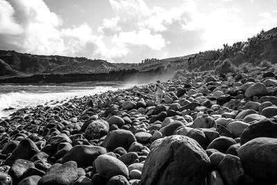 Rear view of man walking on rocky shore