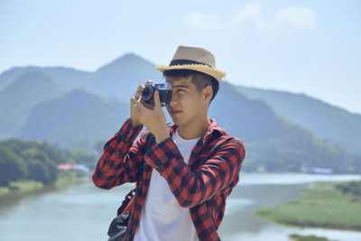 Young asian travel photographer taking pictures outdoors