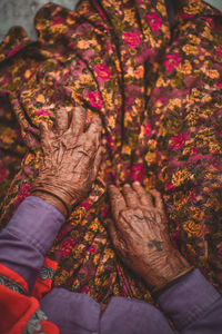 Midsection of senior woman with tattoo on hands sitting outdoors