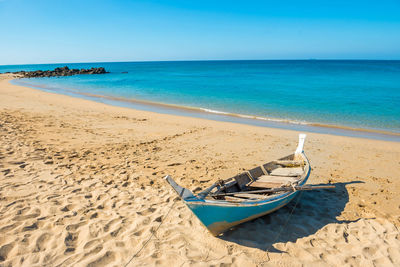 Tropical landscape with boat at sand beach, blue sky and turquoise sea