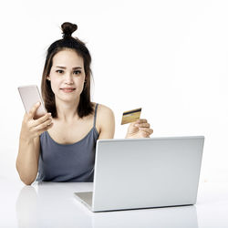 Portrait of smiling young woman using smart phone against white background