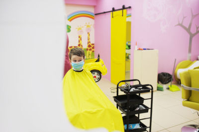 Portrait of boy standing on table at home