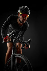 Athlete riding bicycle against black background
